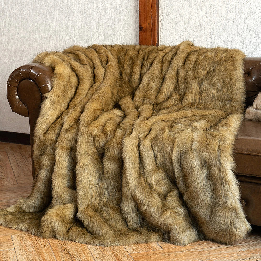 Brown fur throw blanket draped over a brown leather sofa.