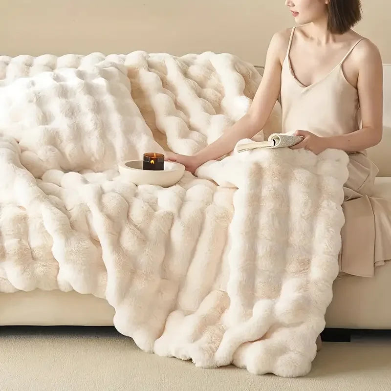 Woman sitting on a couch with a fluffy white blanket and a candle