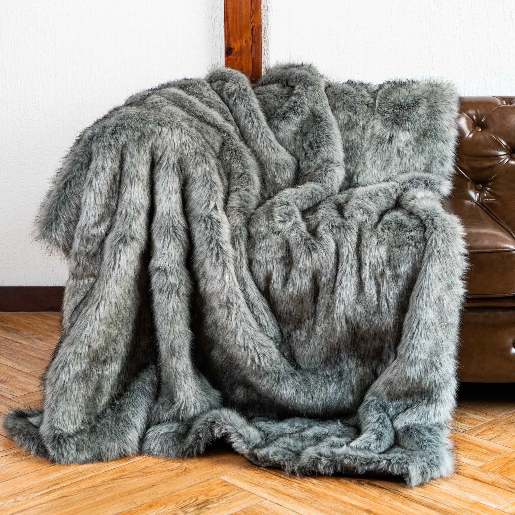 Gray faux fur blanket draped over a chair on a wooden floor.