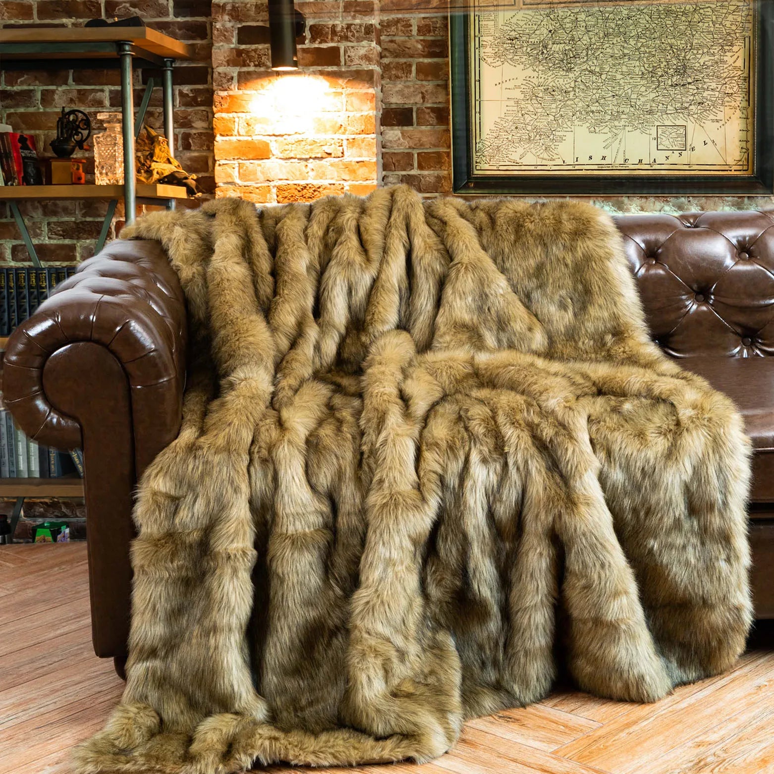 Brown fur throw blanket draped over a brown leather sofa in a cozy room with brick walls and a map.