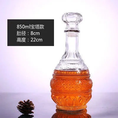 Glass decanter with textured design filled with amber liquid on a reflective surface.