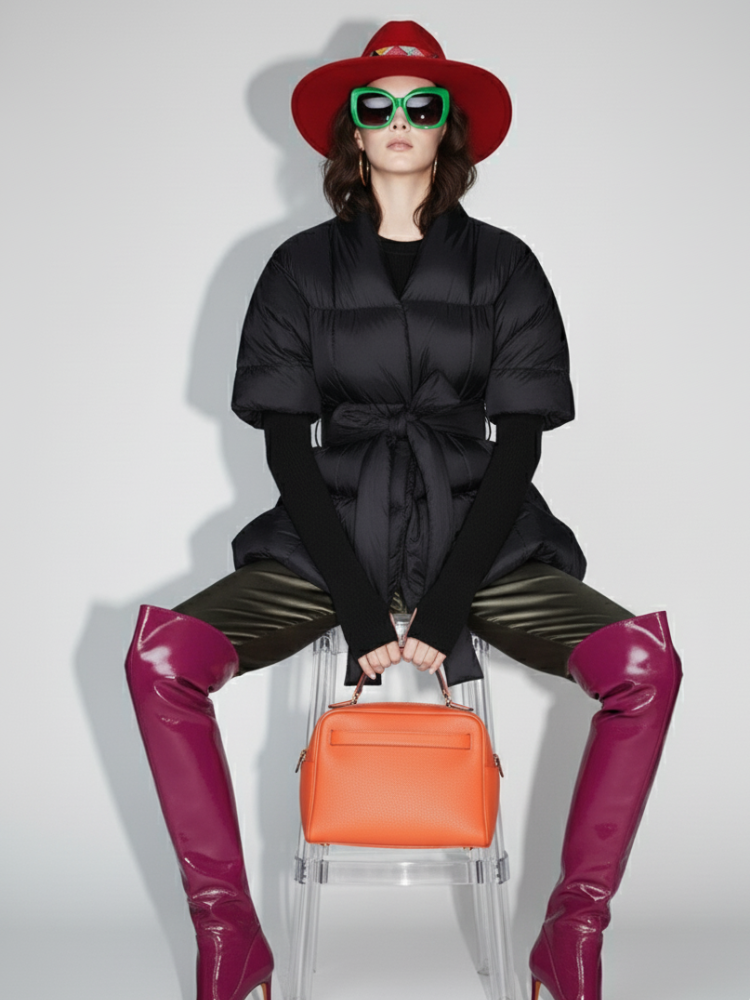 Person wearing a black coat, red hat, green sunglasses, and purple boots with an orange bag on a white background