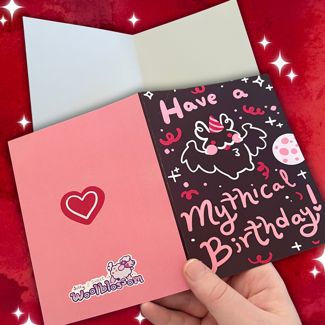 Hand holding a birthday card with a unicorn design on a red background