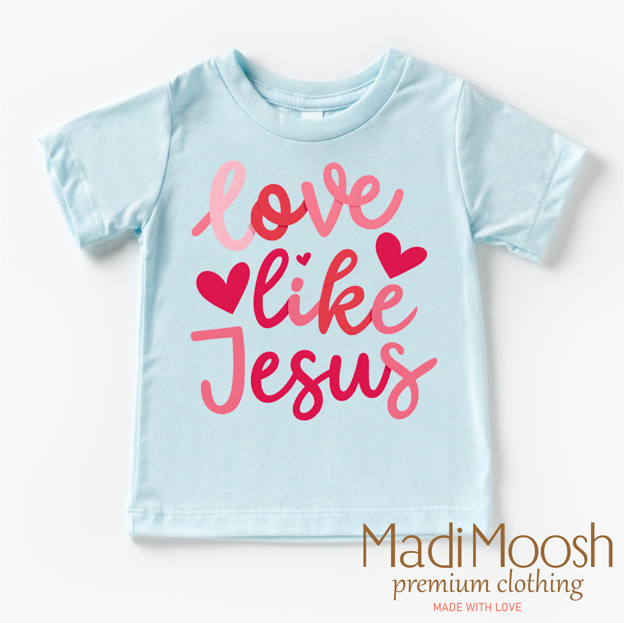 Light blue t-shirt with 'Love like Jesus' text in pink on a white background, branded with Madi Moosh.