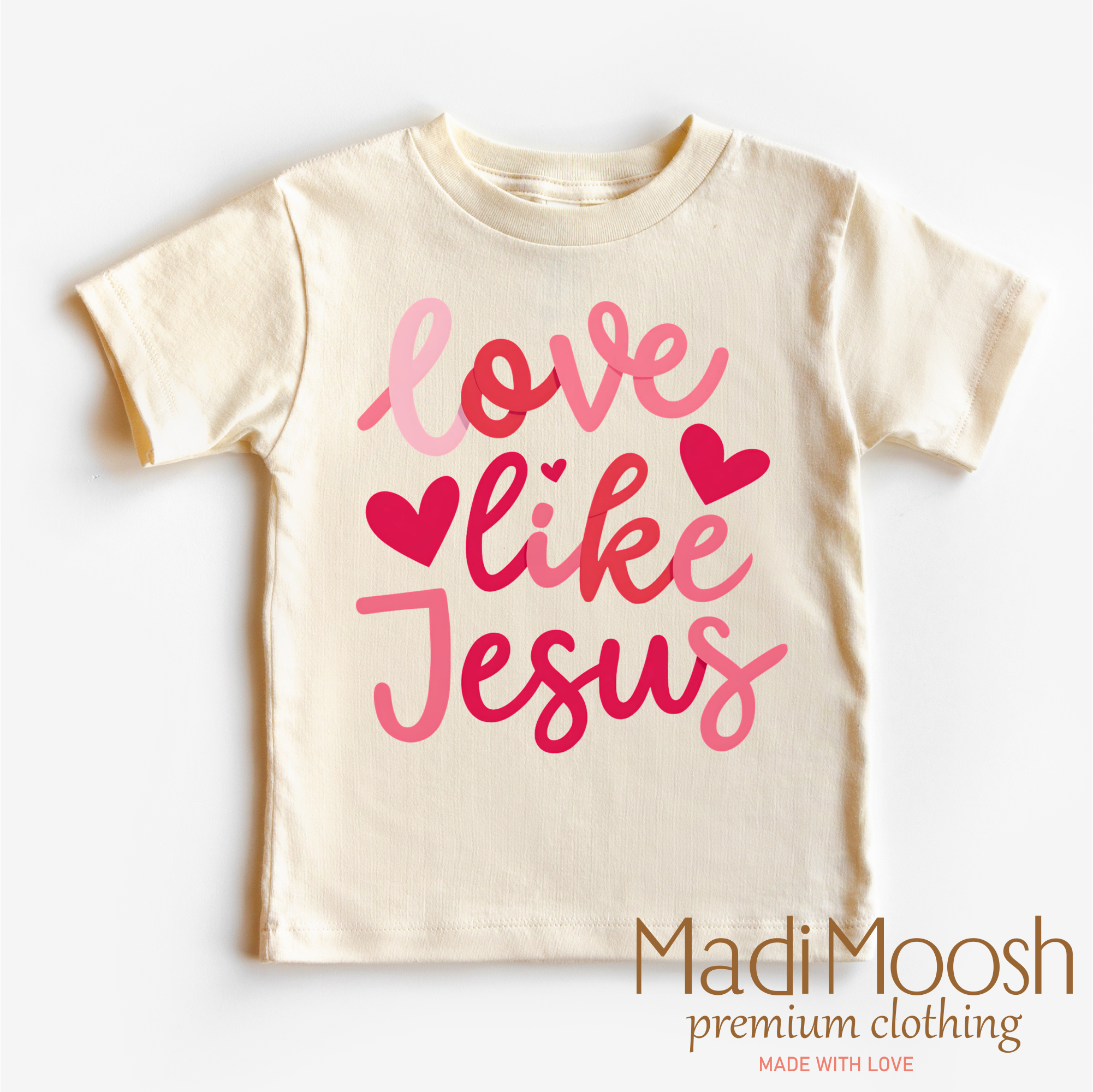 Beige t-shirt with pink 'Love like Jesus' text and hearts on a white background, branded as Madi Moosh.