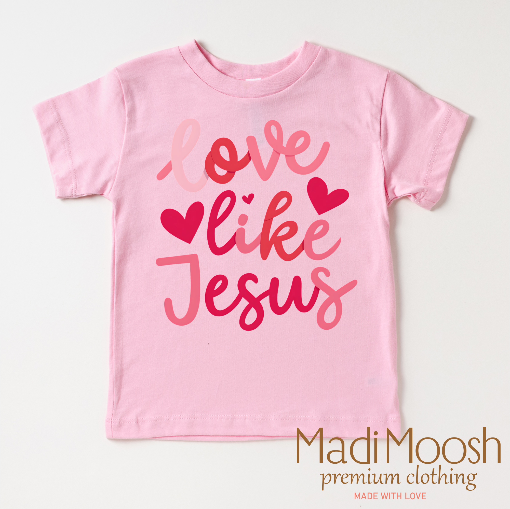 Pink t-shirt with 'Love like Jesus' text and hearts on a white background, branded with Madi Moosh.