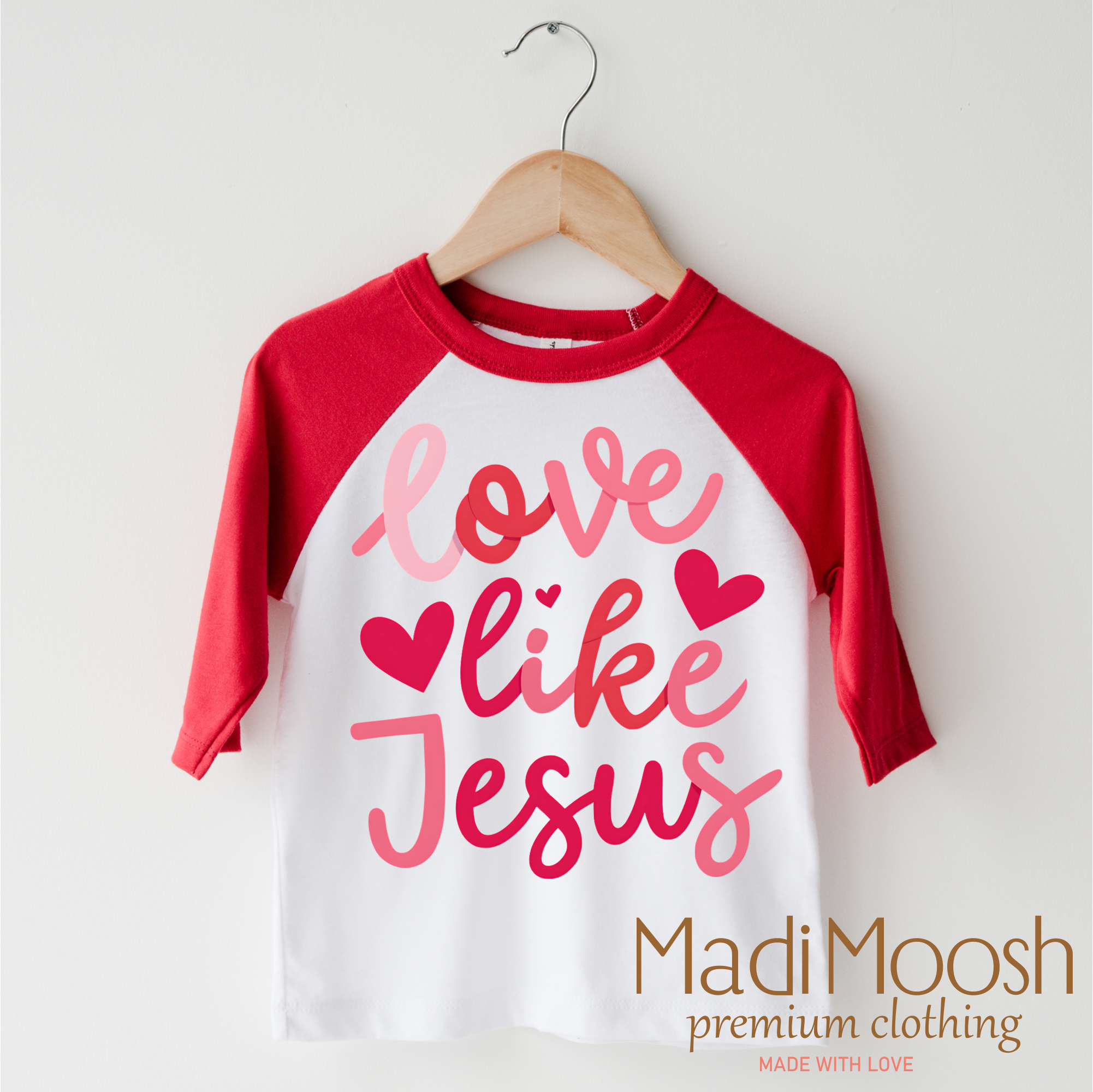 Red and white 3/4 sleeve shirt with 'Love like Jesus' text on a hanger, branded as Madi Moosh.
