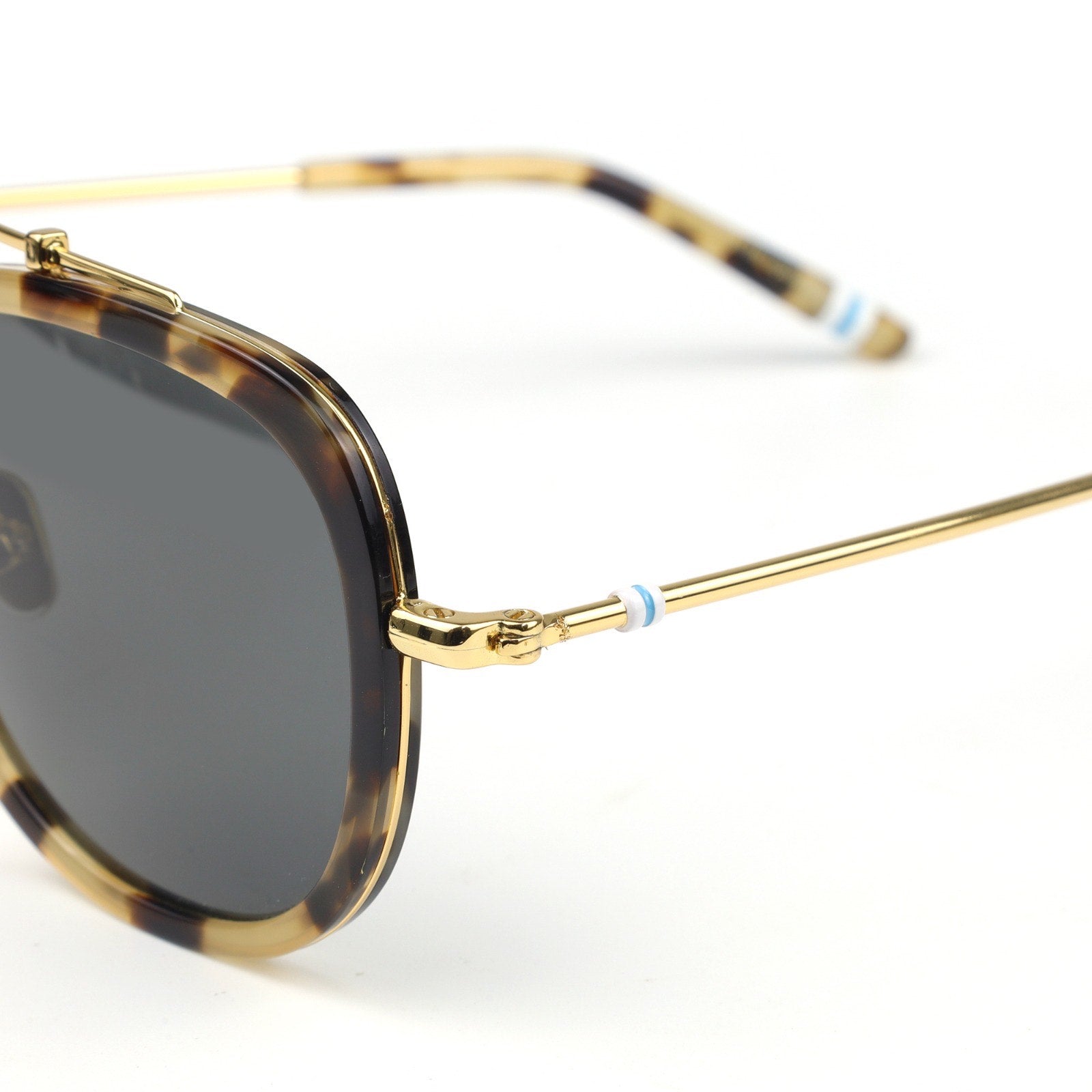 Sunglasses with gold frame and tortoiseshell accents on a white background