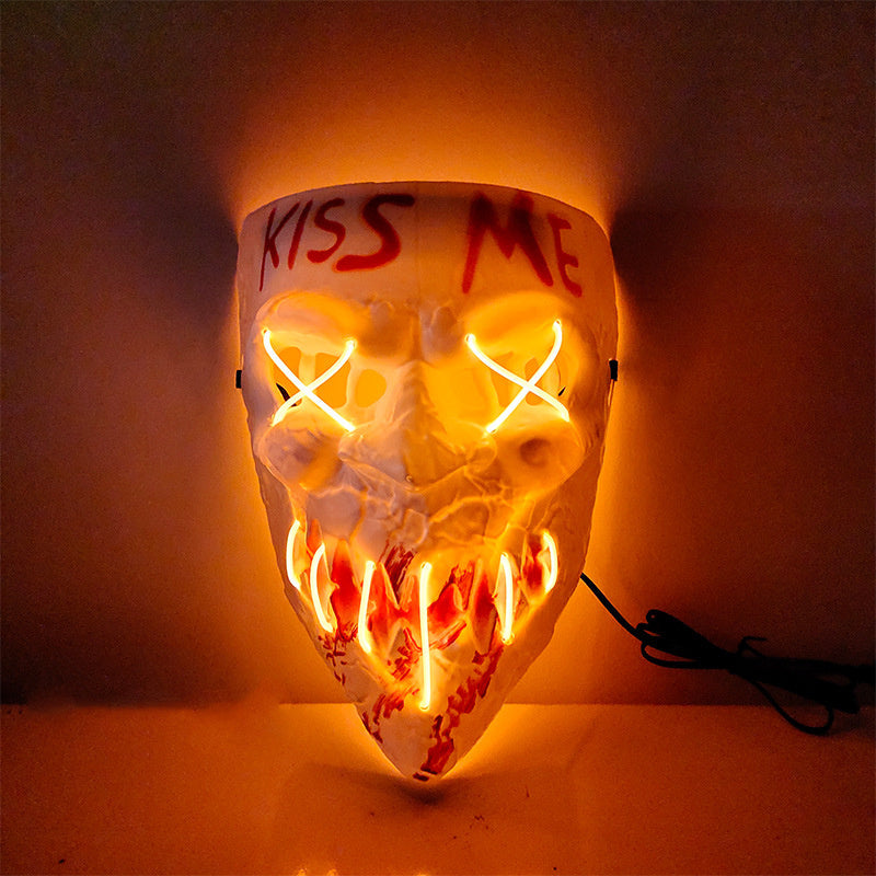LED skeleton mask with 'KISS ME' text on a dark background