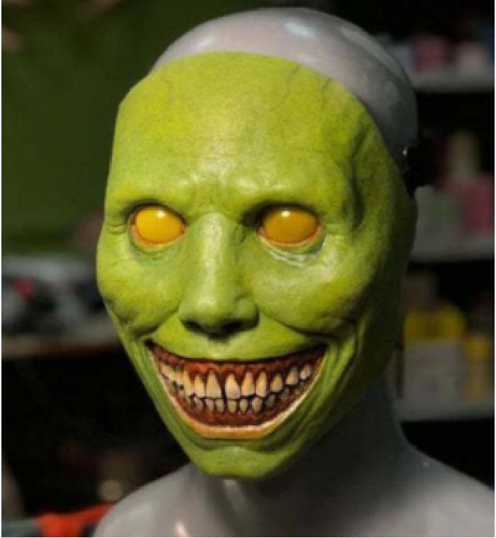 Green mask with yellow eyes and a wide grin on a mannequin head.