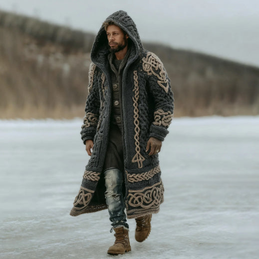 Man wearing a long, patterned coat walking on a snowy landscape.