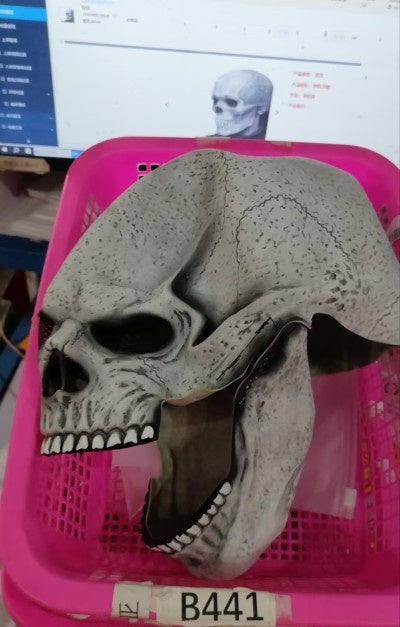 Skull mask on a pink basket with a computer screen in the background
