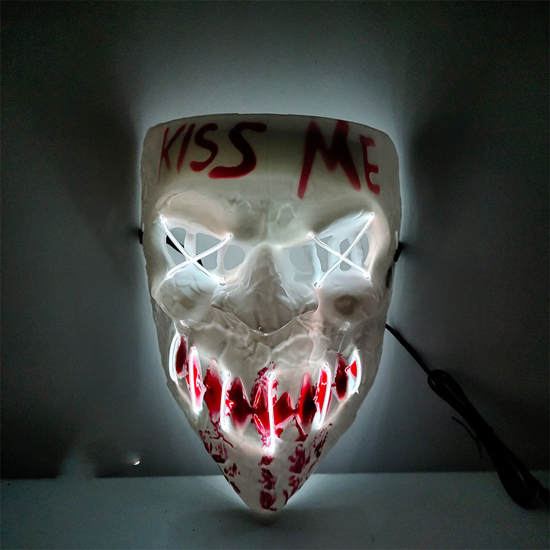Horror-themed mask with glowing eyes and 'KISS ME' text on a dark background