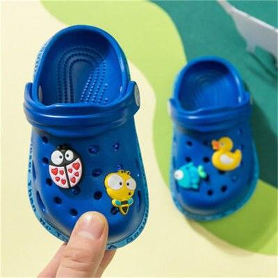 Blue children's clogs with decorative charms on a colorful background