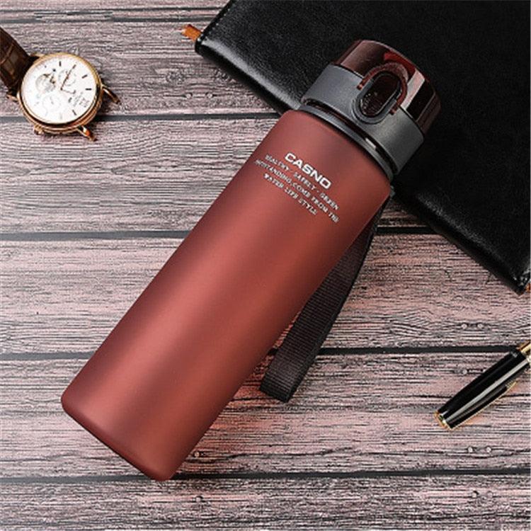 Red water bottle with black lid on a wooden surface, featuring the brand 'Casno'.