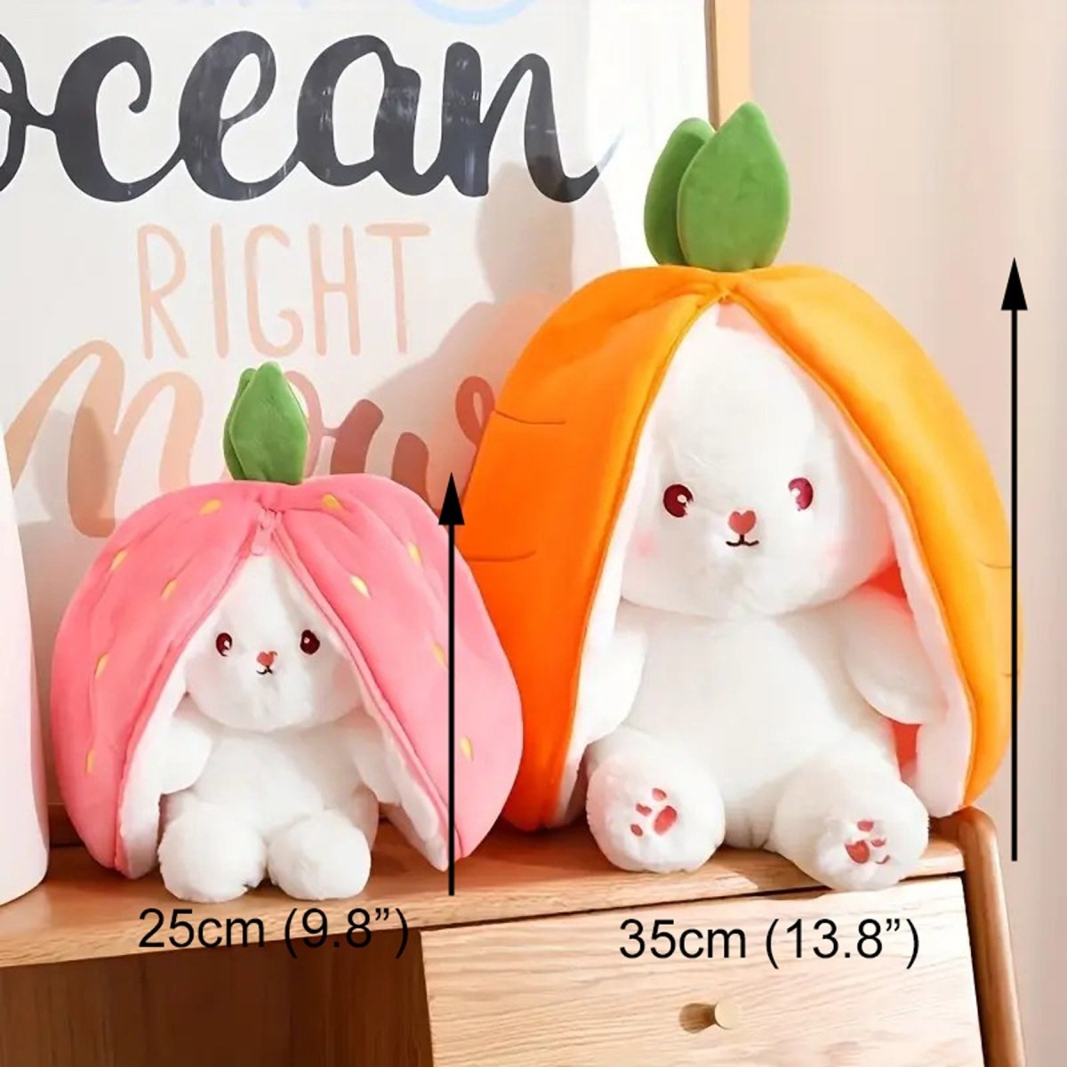 Two plush toys with carrot and strawberry hats on a wooden surface, with measurements indicated.