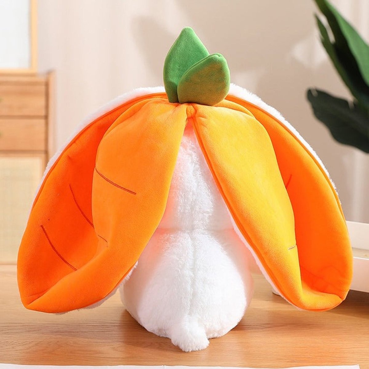 Plush toy shaped like a pumpkin with a green leaf on a wooden surface.