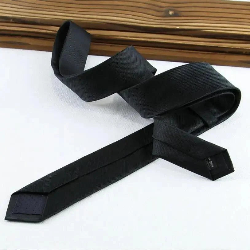 Black tie on a white surface with a wooden background