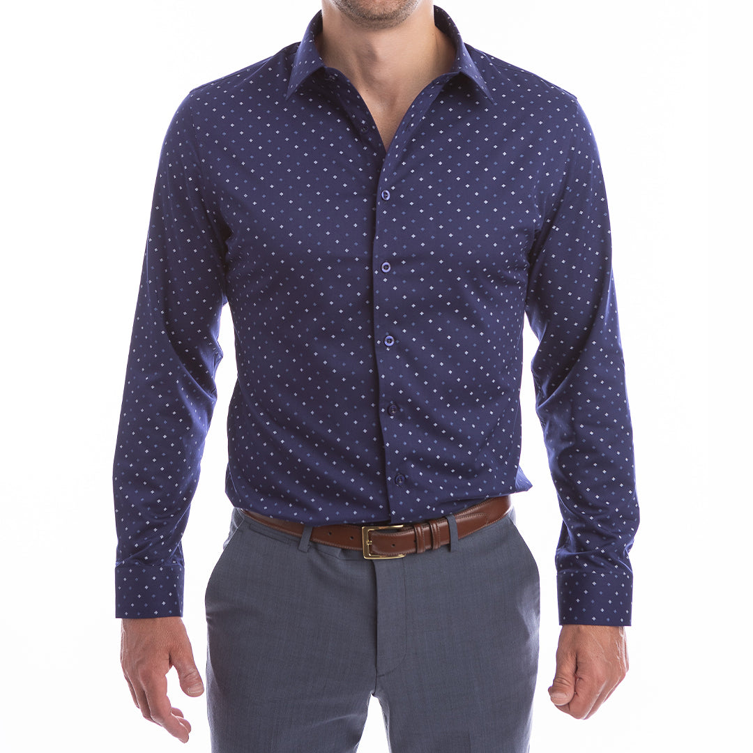 Man wearing a navy blue patterned shirt and gray pants on a white background