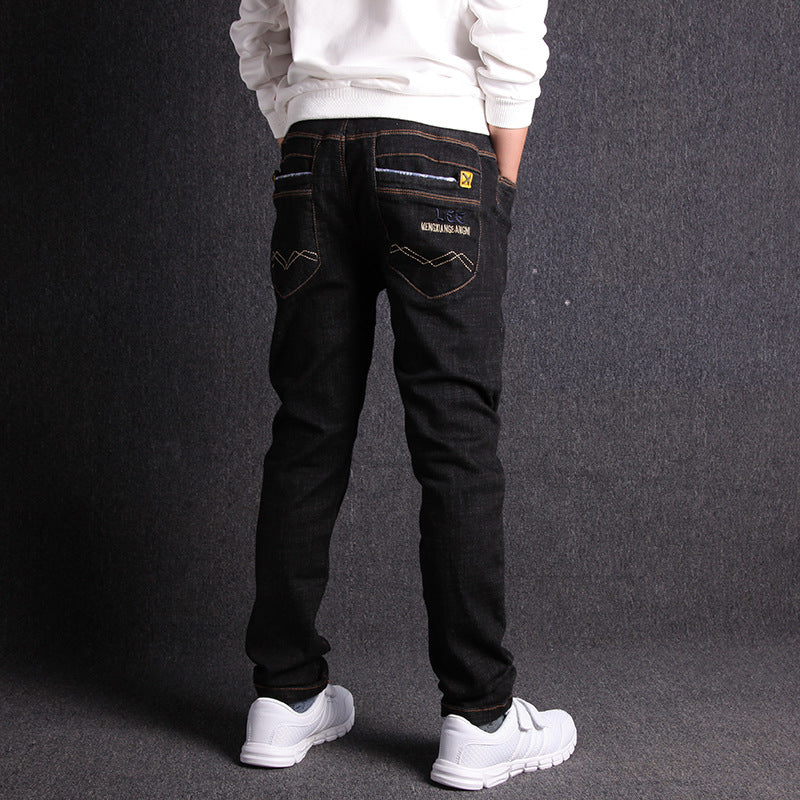 Person wearing black jeans and white sneakers on a dark background