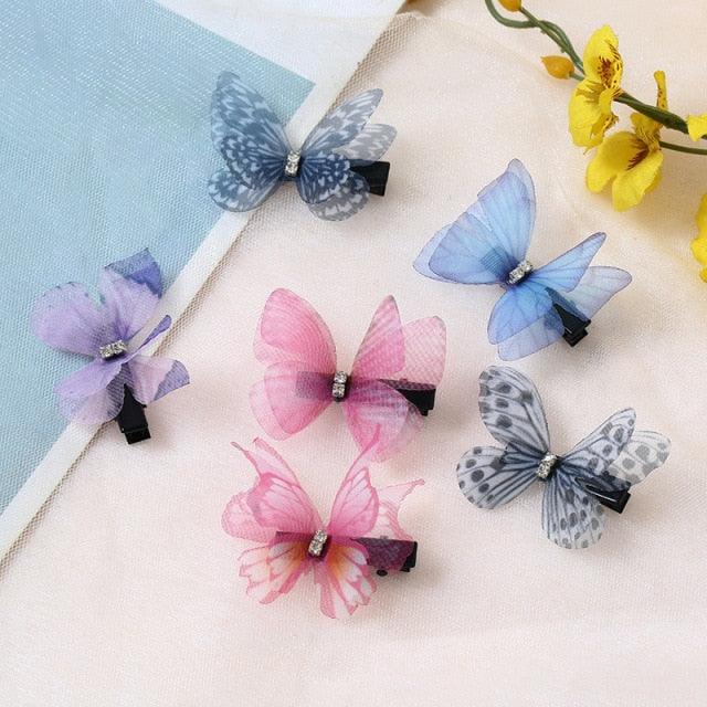 Butterfly-shaped hair clips in various colors on a light surface with flowers in the background.