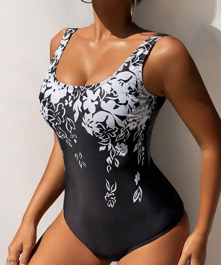 Black swimsuit with white floral patterns worn by a person against a light background