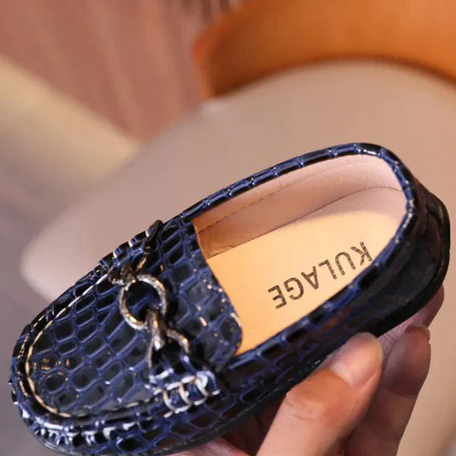 Blue loafers with a brand name on the insole held by a hand.
