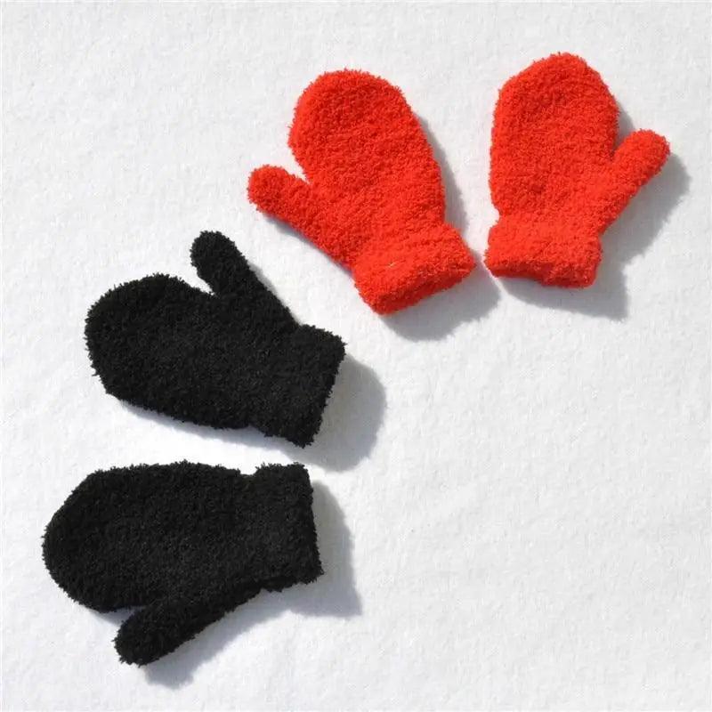 Two pairs of red and black fuzzy gloves on a white background