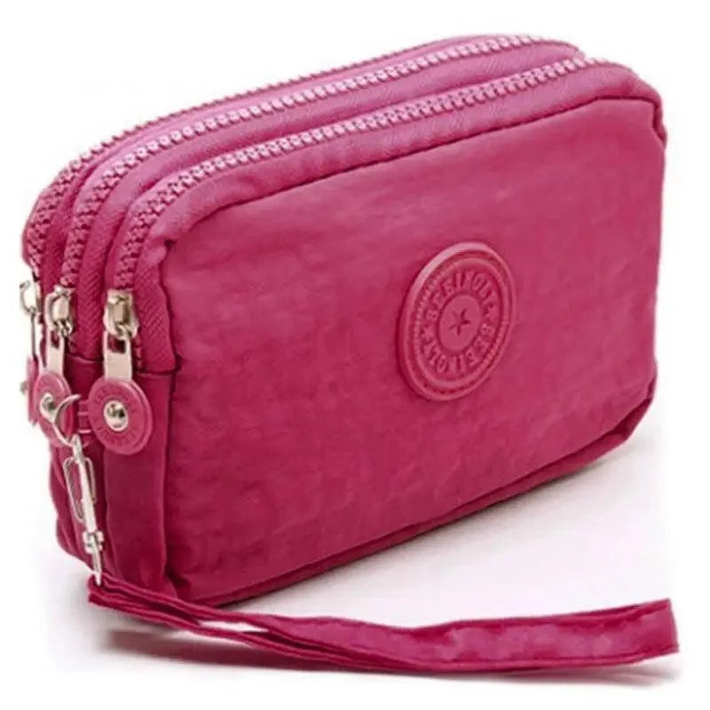 Pink wristlet with multiple zippers on a white background