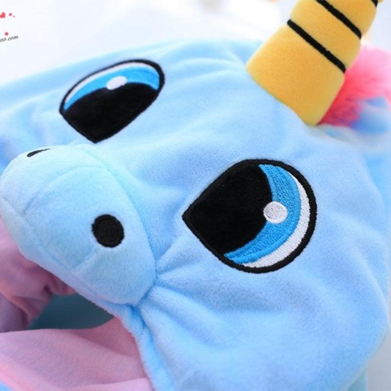 Close-up of a blue plush toy with large black eyes and a yellow horn.