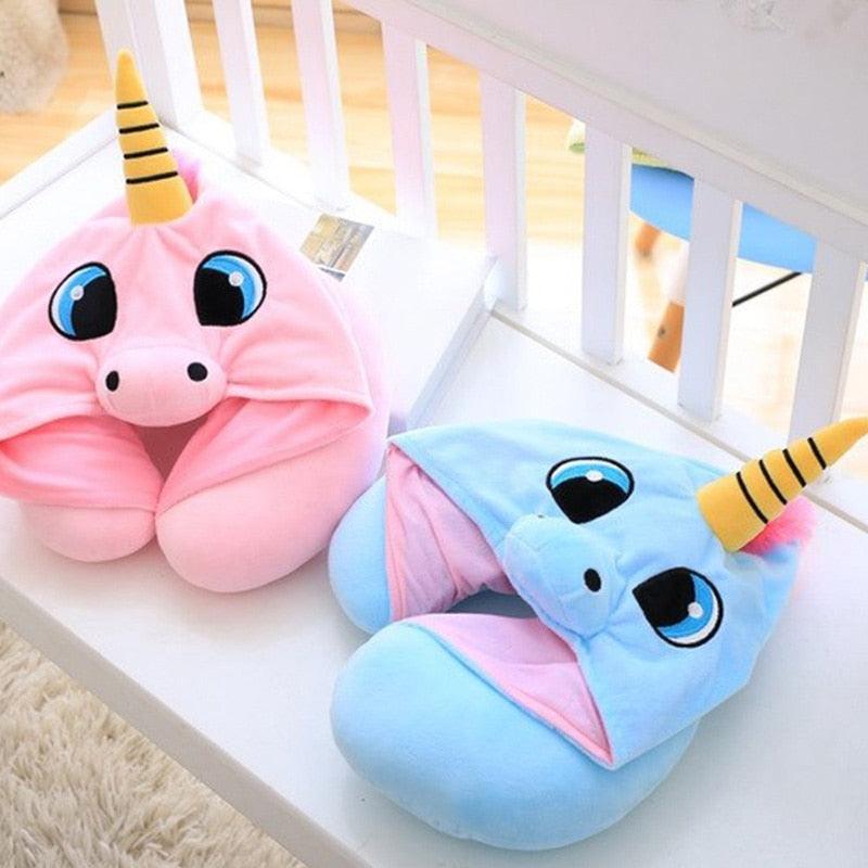 Pink and blue unicorn-shaped slippers on a white surface.