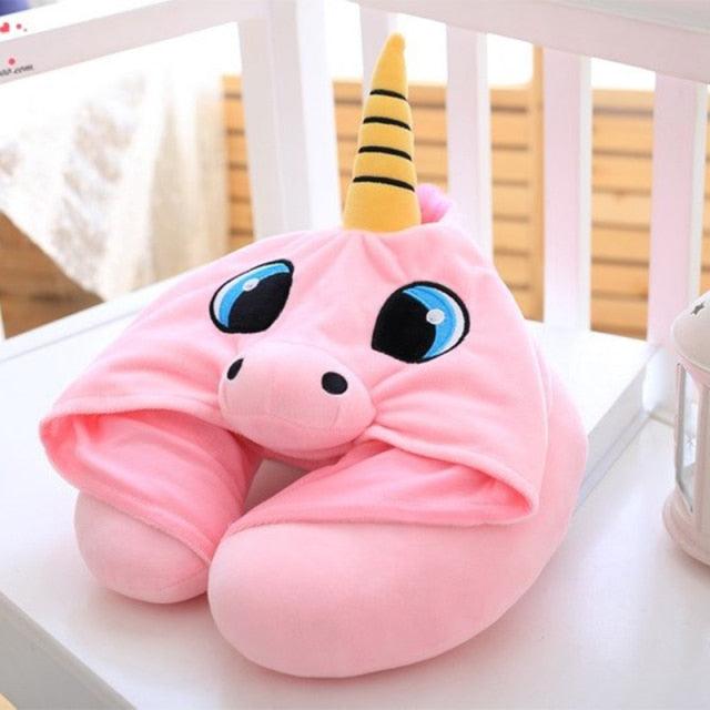 Pink unicorn-shaped neck pillow with a yellow horn on a white surface.