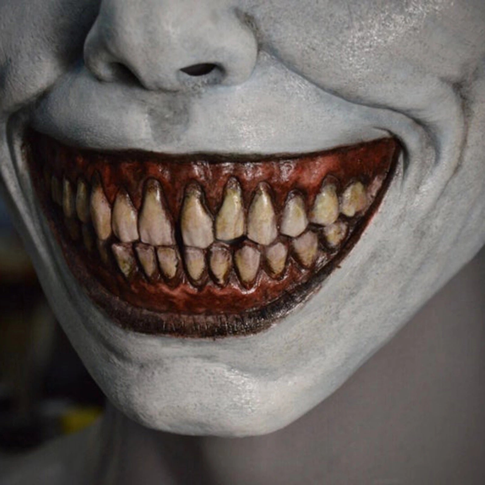 Close-up of a person with a clown-like makeup and exaggerated smile.
