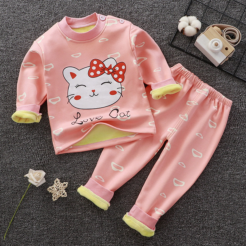 Children's pink pajama set with a cat design on a gray surface.