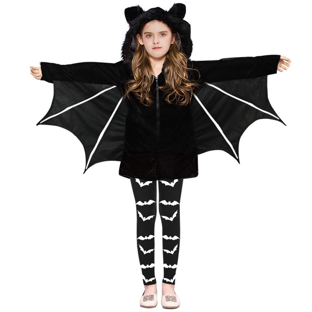 A child wearing a black bat costume with attached wings, a black hood with cat ears, and black-and-white patterned leggings, posed against a plain white background.