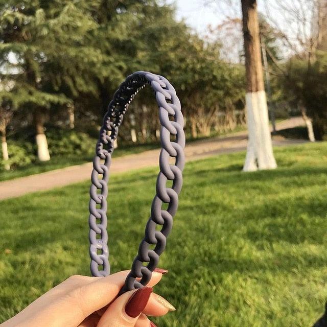 Person holding a gray chain-like object with a park in the background