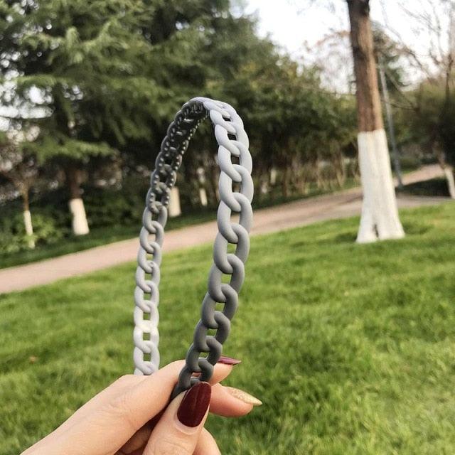 Person holding a gray chain-shaped object with a park background