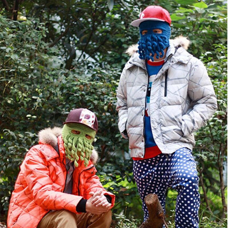 Two people wearing colorful masks and winter clothing in a forest setting.