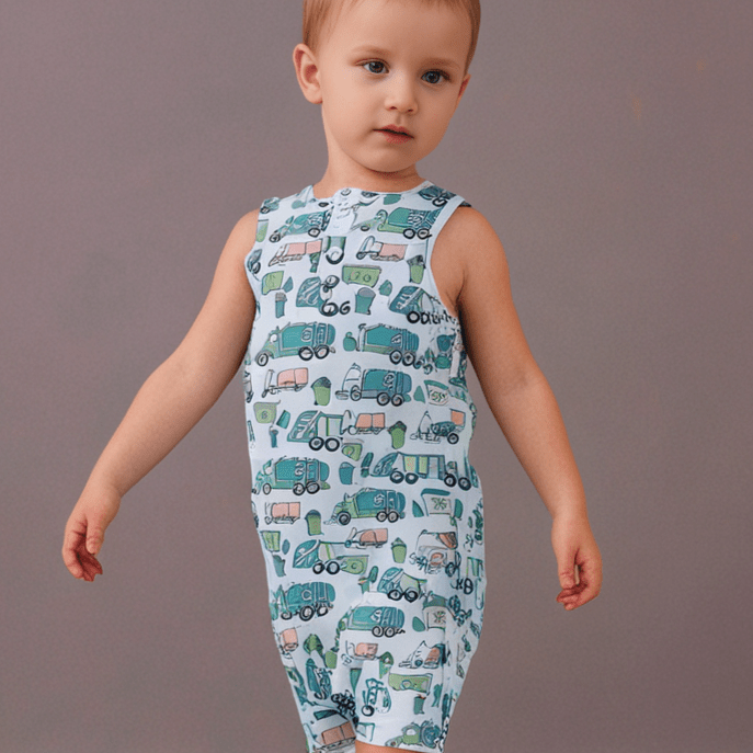 Child wearing a sleeveless romper with truck pattern on a plain background