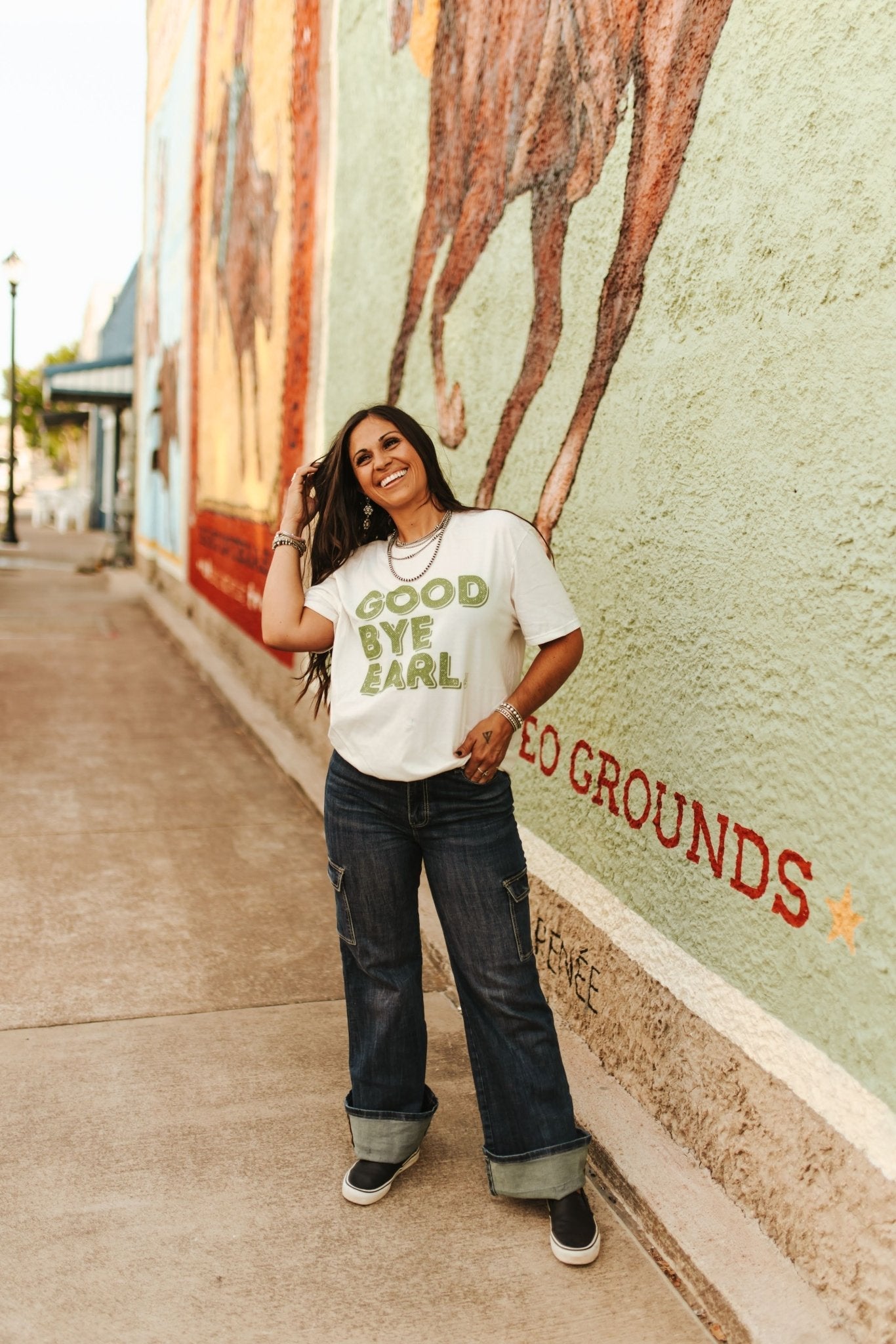 Woman standing in front of a mural with text on a wall.