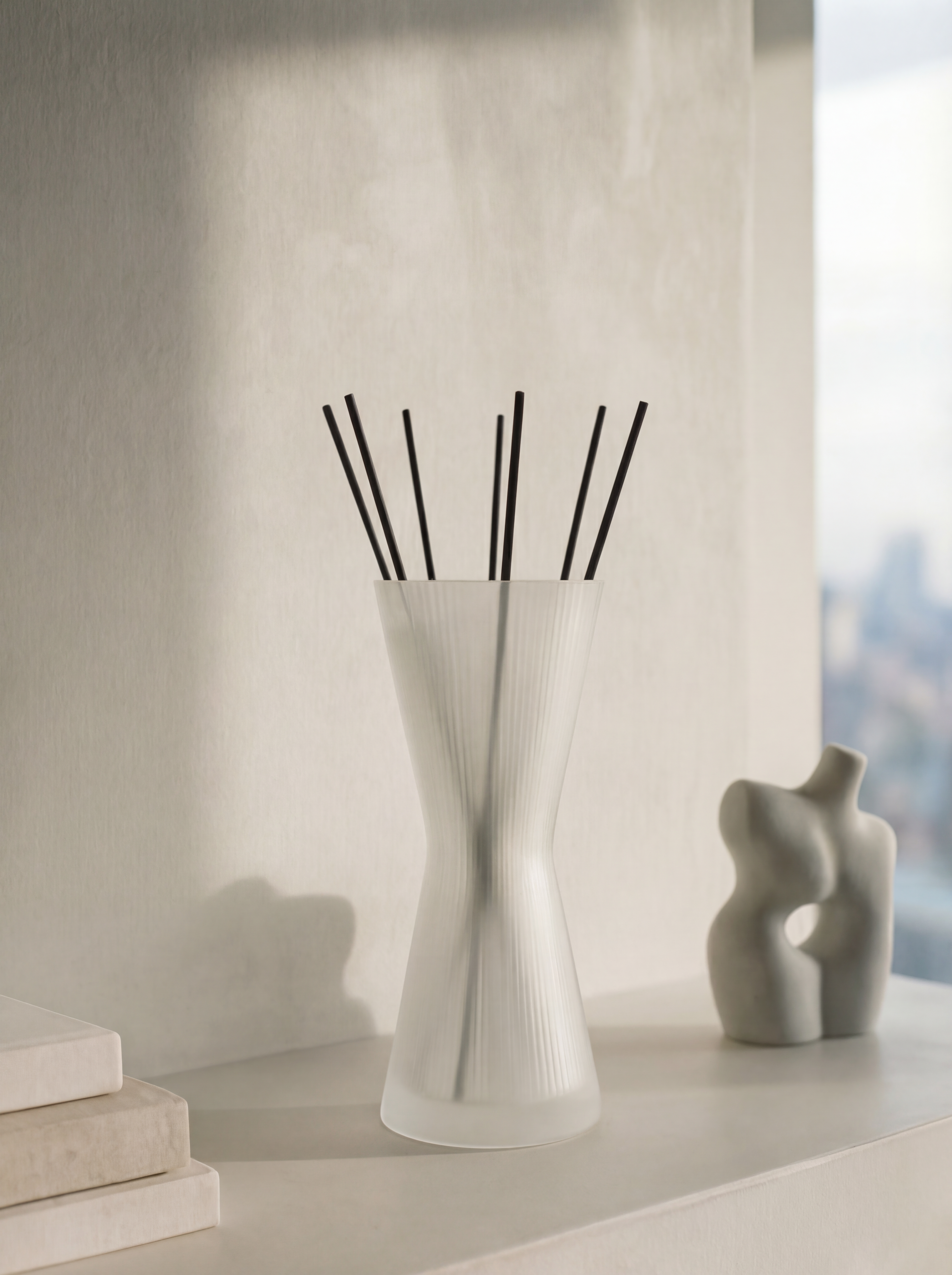 White diffuser vase with black sticks on a light surface with a blurred background