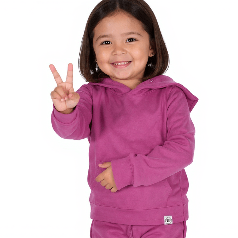 Child wearing a pink hoodie and pants, making a peace sign on a white background