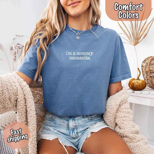 Person wearing a blue t-shirt with text, sitting on a couch.
