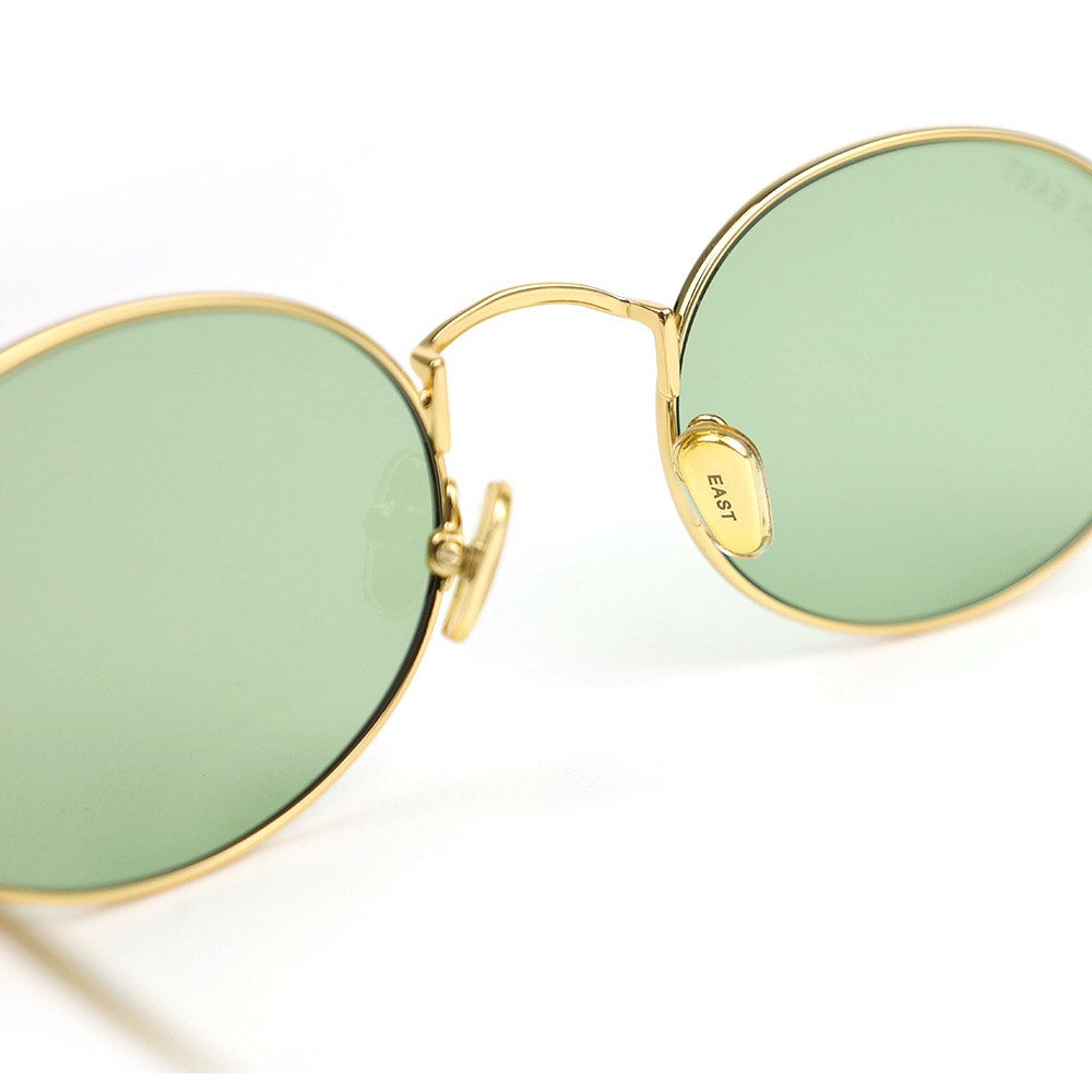 Gold-framed sunglasses with green lenses on a white background