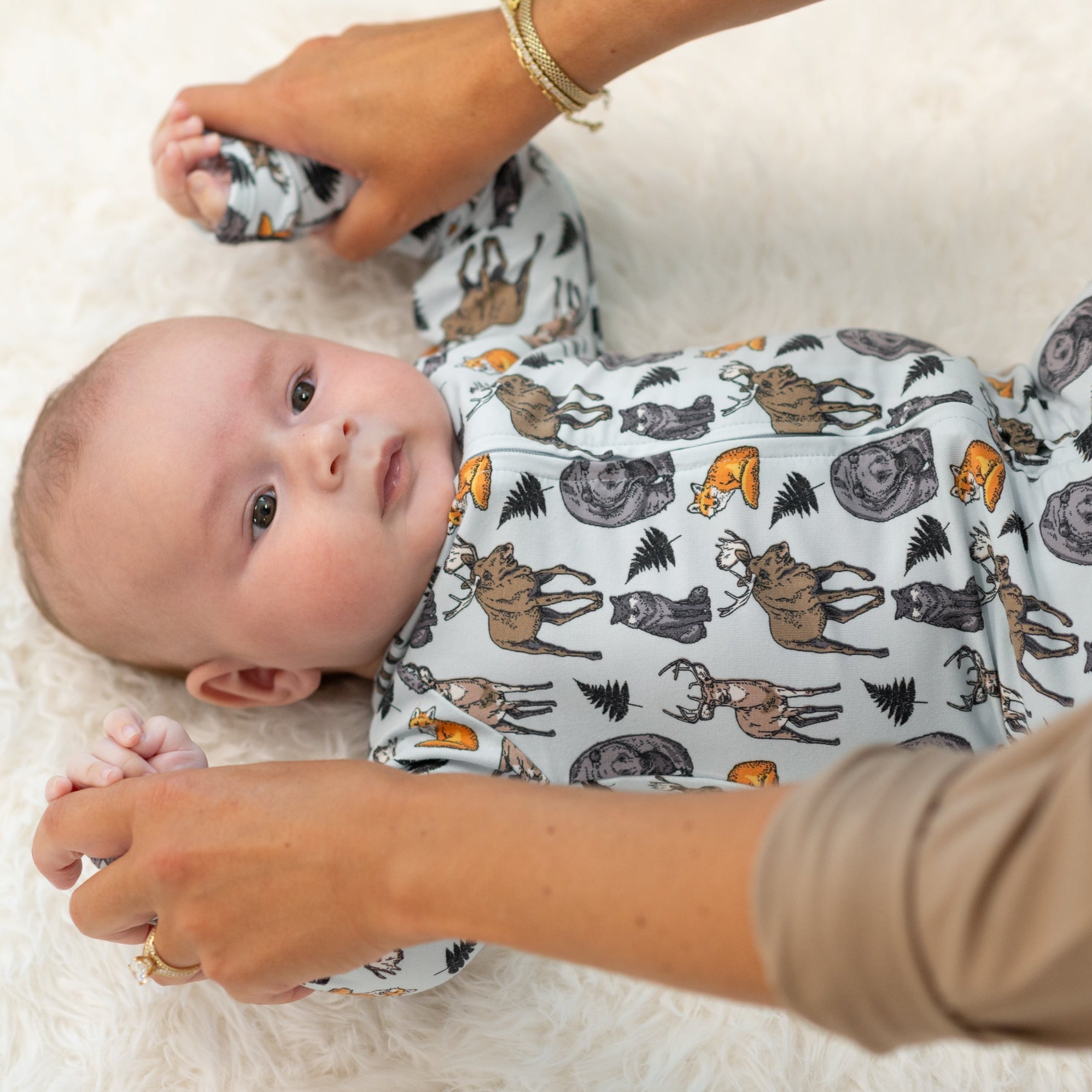 Baby wearing a onesie with animal pattern, lying on a soft surface.