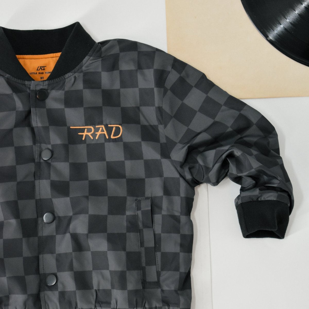 Black and gray checkered jacket with 'RAD' embroidery on a white surface.