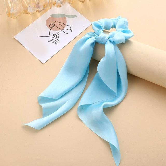 Light blue hair tie with a decorative bow on a beige surface