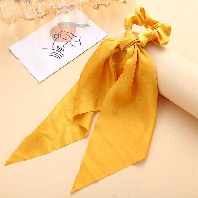 Yellow hair scarf with a bow on a beige surface