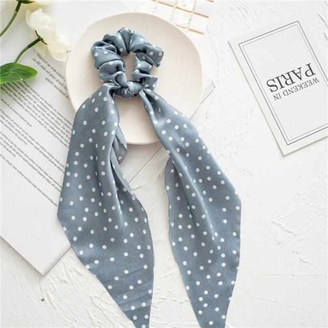 Gray polka dot scarf with a scrunchie on a white surface