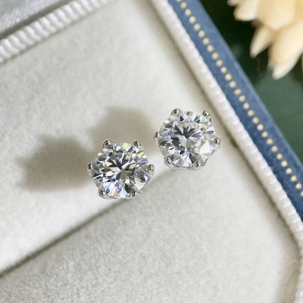 Pair of silver stud earrings with clear gemstones on a light gray surface.